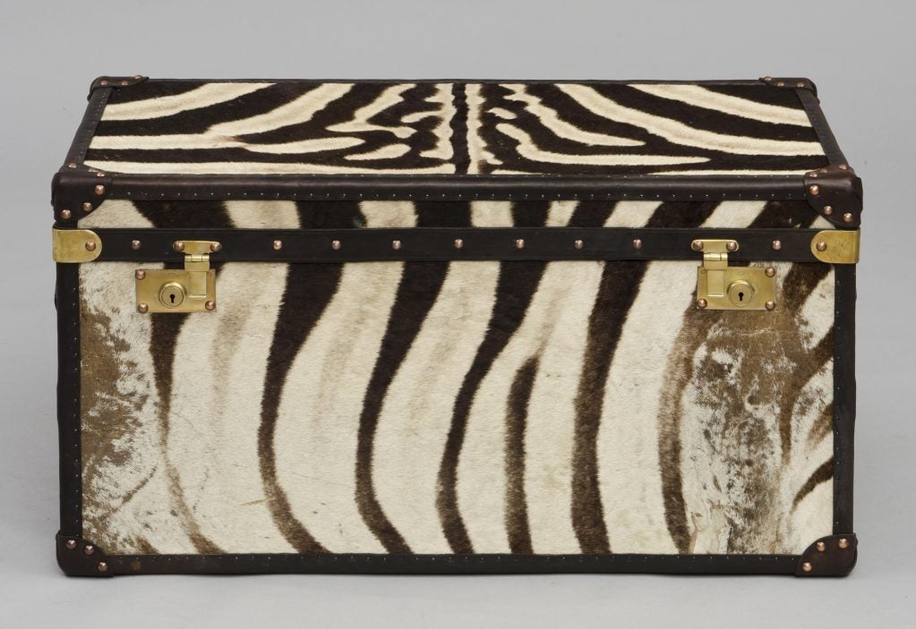 Custom hand-made leather trunk re-purposed from antique leather suitcases and covered in vintage zebra skin rugs.  The inside is lined in a red and gold striped cotton.  New brass locks and copper tacks.