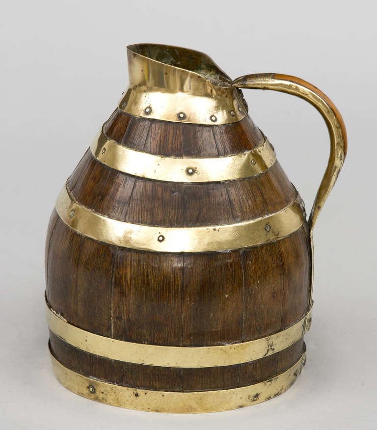 Finely crafted small oak coopered jug with brass banding, the spout and handle also brass bound.

 