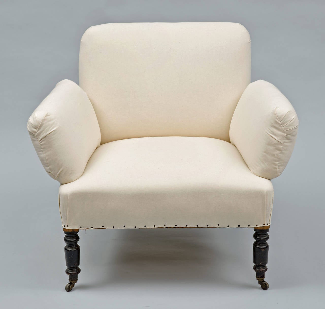 The arms are unusual because they are detached from the back, the turned front legs on casters are ebonized and the chair is upholstered in white muslin. It is very comfortable.

     