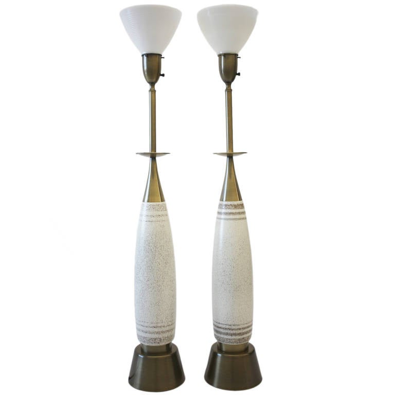 These towering svelte table lamps crafted by Rembrandt Lamp Co. have two matching, yet slightly different glazed pottery bodies. The hardware on both have been beautifully replated in antique brass, with milk glass diffusers supporting white linen