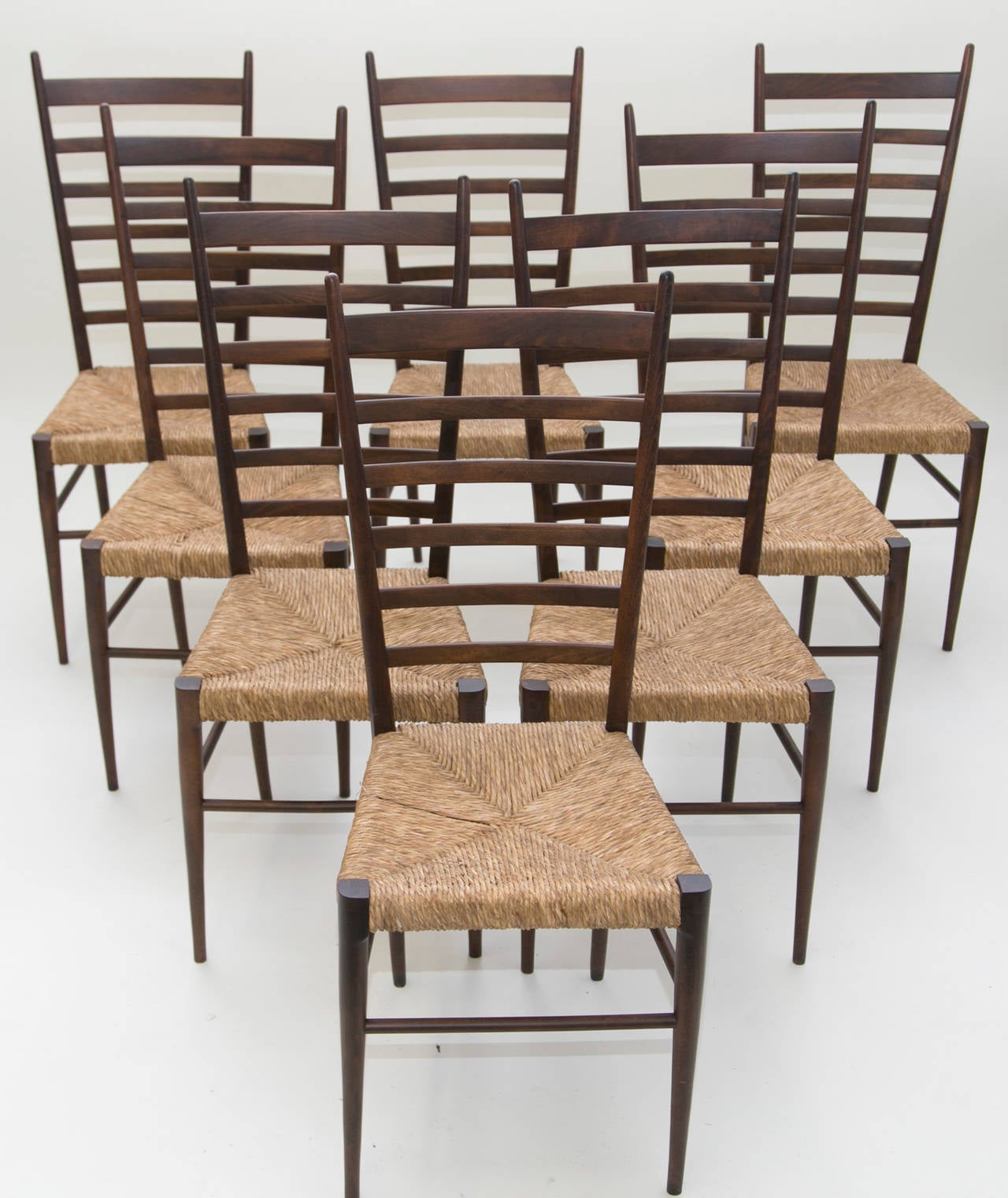 A beautiful set of eight beech wood, ladder back chairs in the style of Gio Ponti. 

Lightweight and simple, these chairs feature expertly rushed seats and newly restored frames.