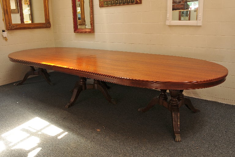 This impressive 14' mahogany dining table, originally housed in the Sinclair Oil Company headquarters, features three pedestal supports with bronze claw-feet.