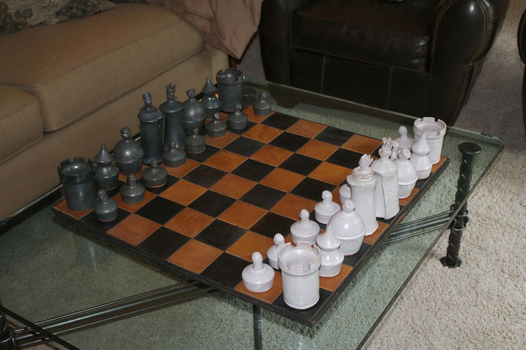 A magnificent hand thrown art pottery chess set of large scale with a hand made leather patch board. Each piece is unique and as mentioned hand thrown. No two art exactly alike. The board is plywood painted black and then the artist hand cut and