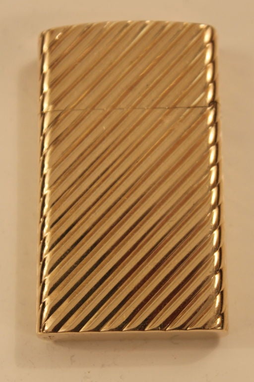 An elegant Cartier 14k gold lighter in a diagonal ribbed pattern. Marked cartier 14k on the base and the interior lighter unit slips out. It is a Zippo unit typical for the time. The case itself without the lighter unit weighs over 20 dwts, which is