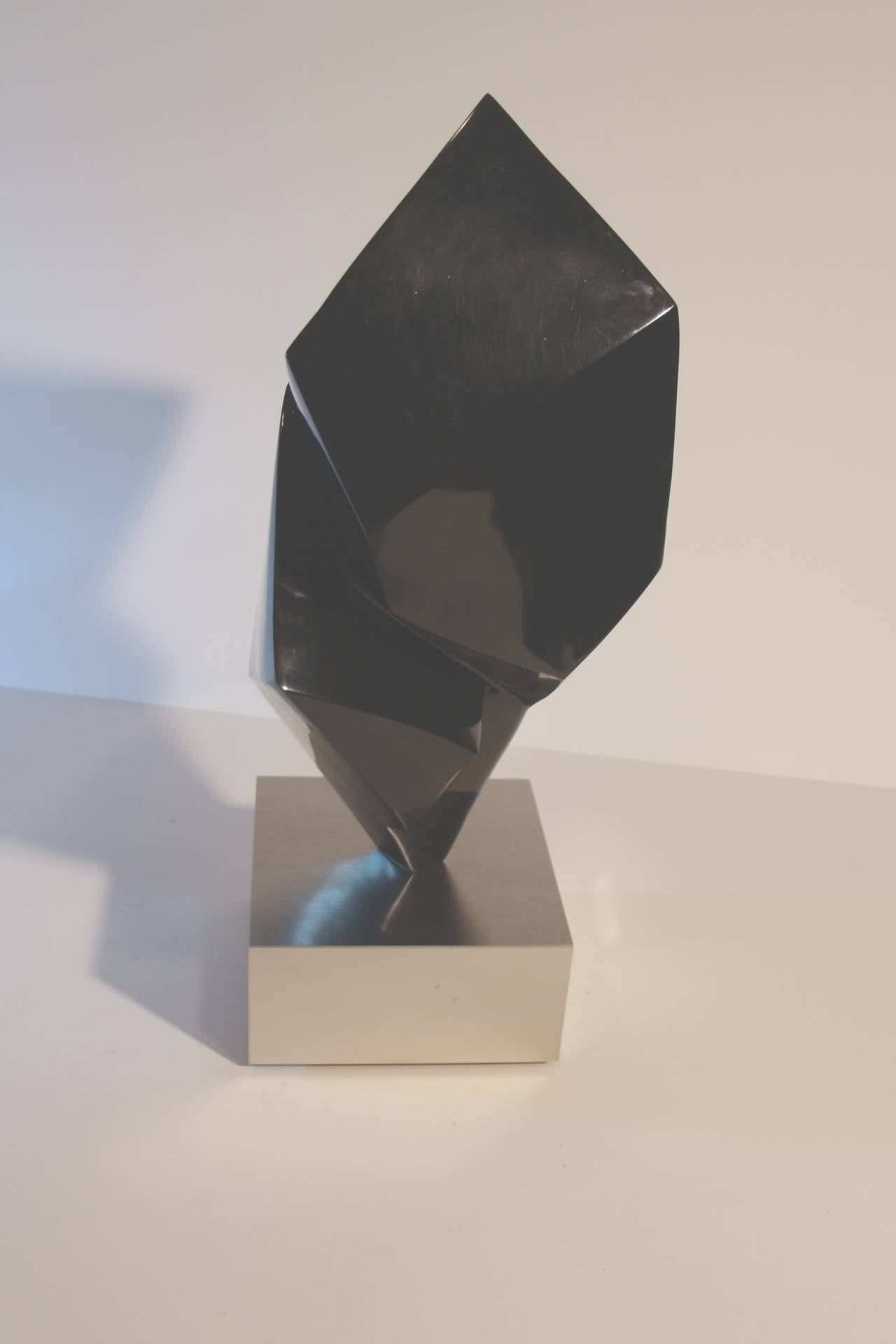 A unique Cubist looking glass sculpture mounted on a rotating metal base with a plaque with her name on it. It is also titled 