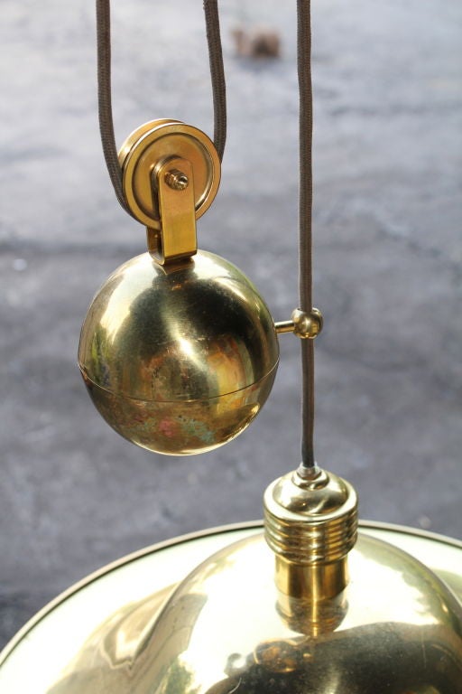 An unusual adjustable cantilevered brass hanging fixture. It rises and lowers on a heavy counter weight system.