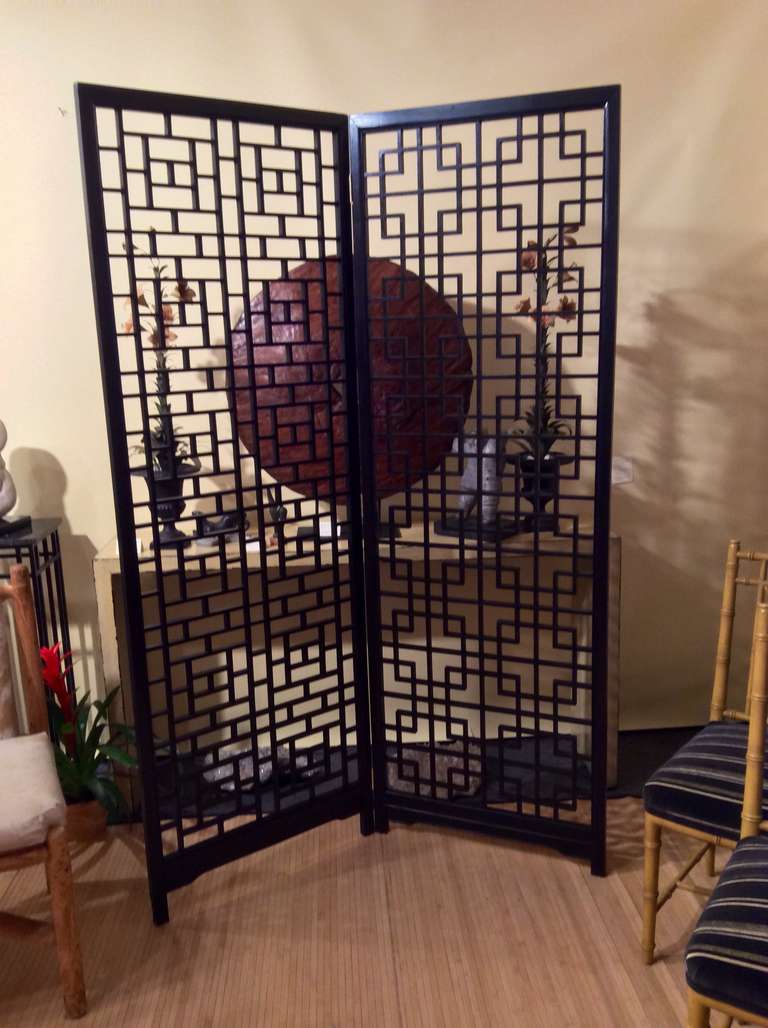 A beautiful Asian wood geometric screen or room divider. New hinges have been put in in place of the old ones. This very functional unit serves to break up a space while still leaving an open feeling. 
Please note the side are not exactly equal in