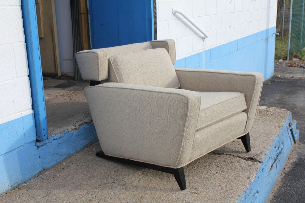 An unusual pair of mid century modern wing/club  chairs on sleigh like legs. The chairs have wood supports holding up the wrap around tops. A great and unusual pair  of chairs, but unfortunately  we don't know who to credit for the design.