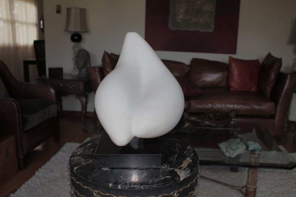 A sensuous white Carrara marble sculpture on a black marble or slate tiered base. It was dated to the 1960s for us from the estate we purchased it from. The sculpture was purchased from the estate of a hedge fund magnate who bought and sold sold