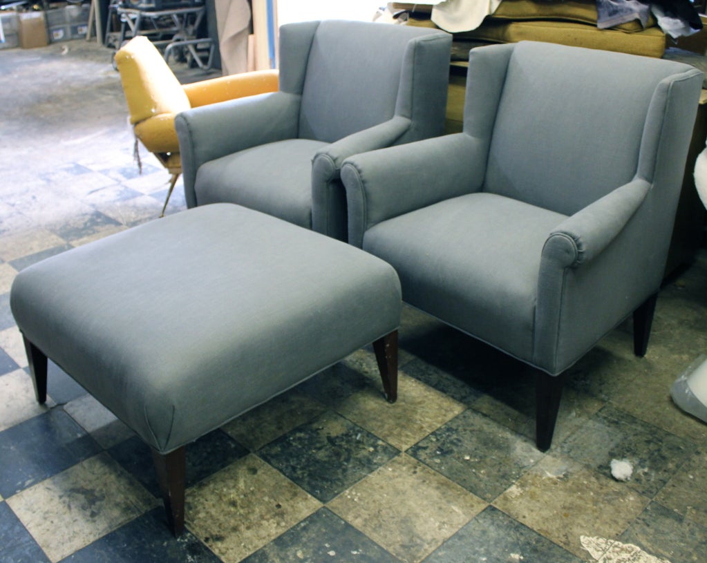 Pair of stylized Baker wing chairs with an ottoman