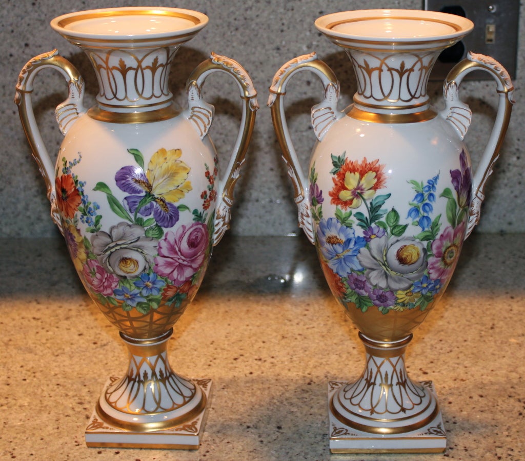 A beautiful pair of Dresden signed porcelain urns with handles. Nice hand painted decoration. Marked on the base.