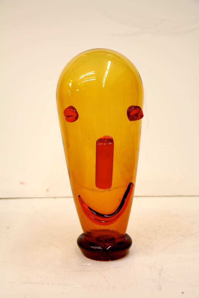 A whimsical glass face with applied features.