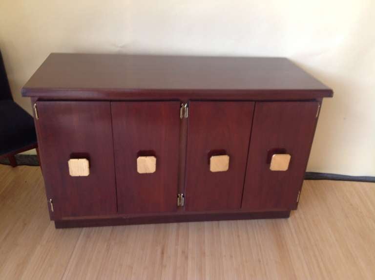 A stunning high quality solid  mahogany 4 door cabinet with beautiful large brass pulls. There are two interior compartments with one shelf in each. The back is solid wood.