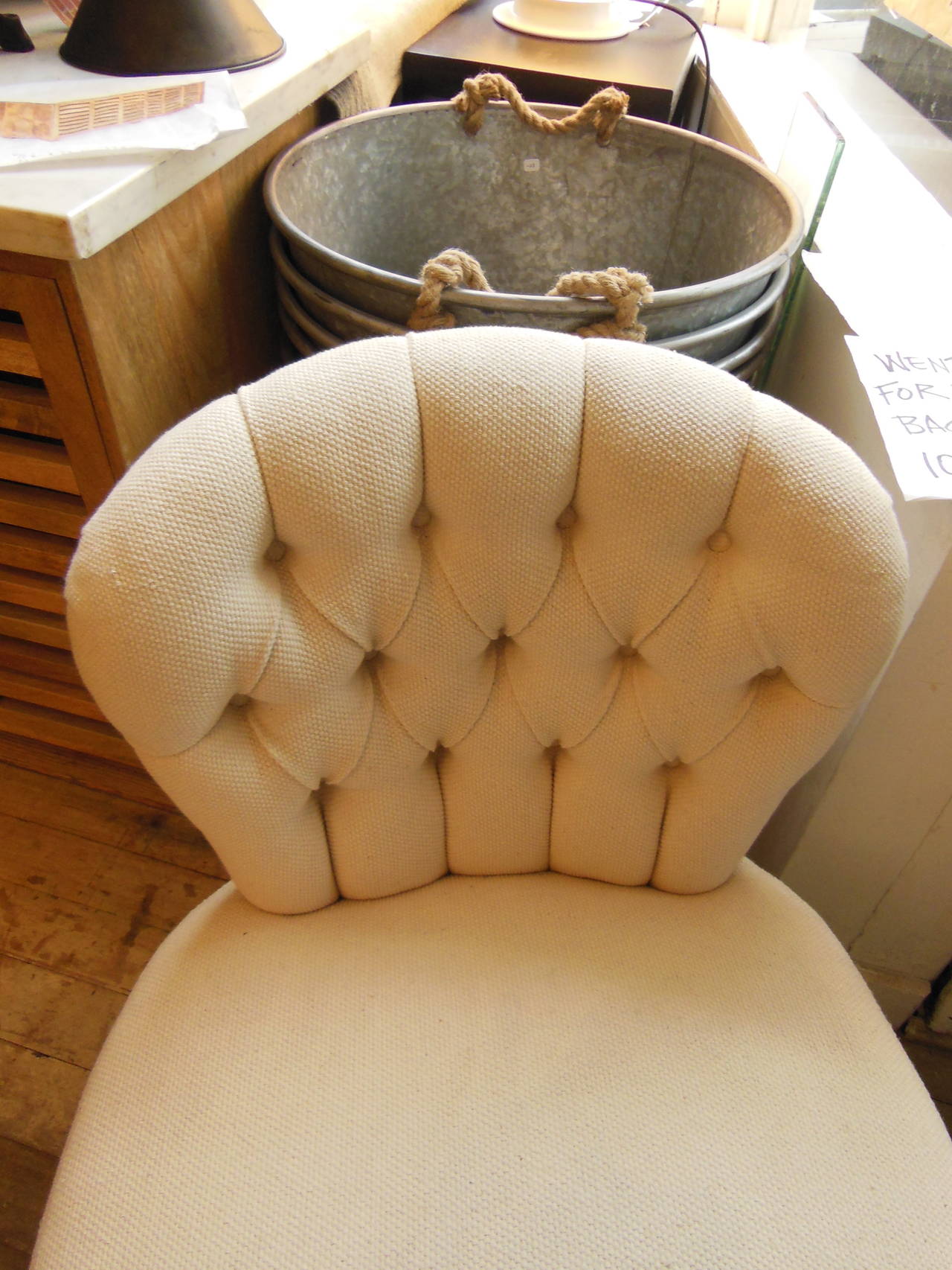 a small tufted back Edwardian chair newly redone in ivory linen on turned legs with casters