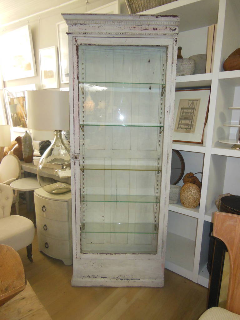 a tall vintage cabinet probably from a pharmacy with glass shelves in old
paint with great patina