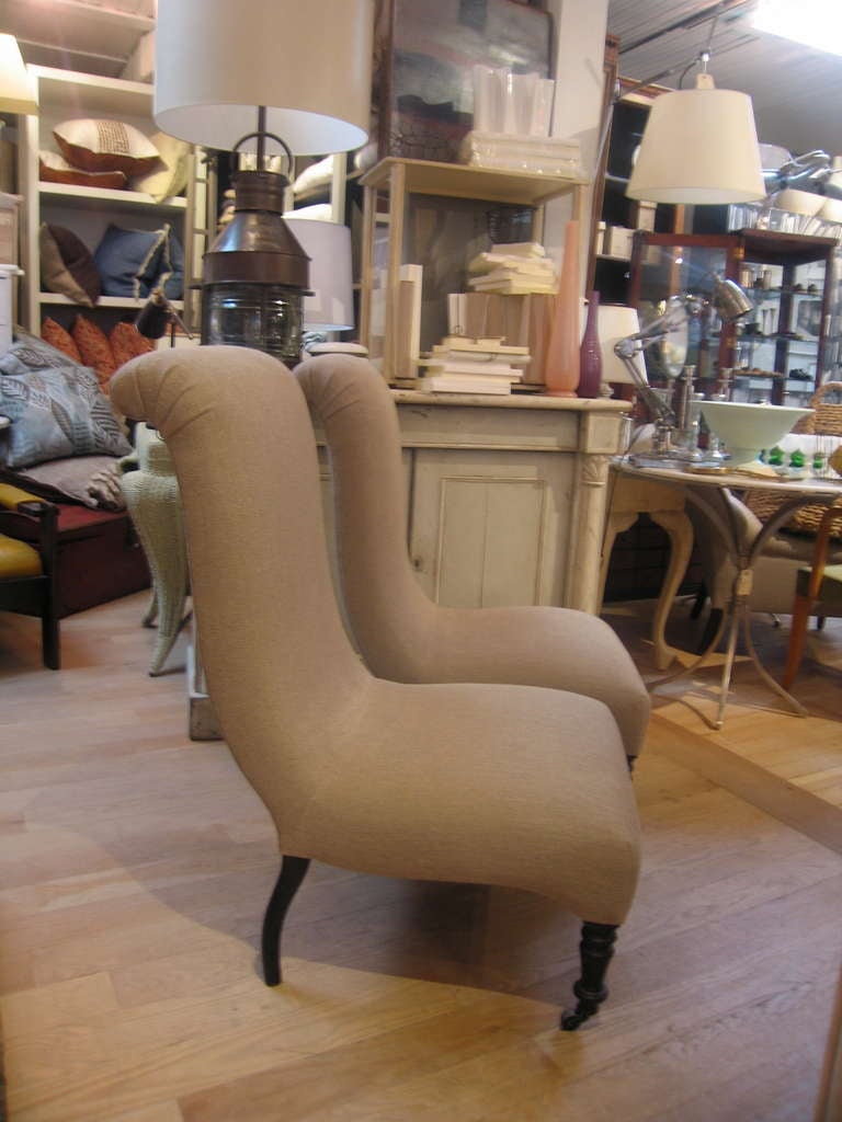 Fine unusual pair of vintage slipper chairs, beautiful form, newly reupholstered in natural Belgian linen on turned dark legs with casters.