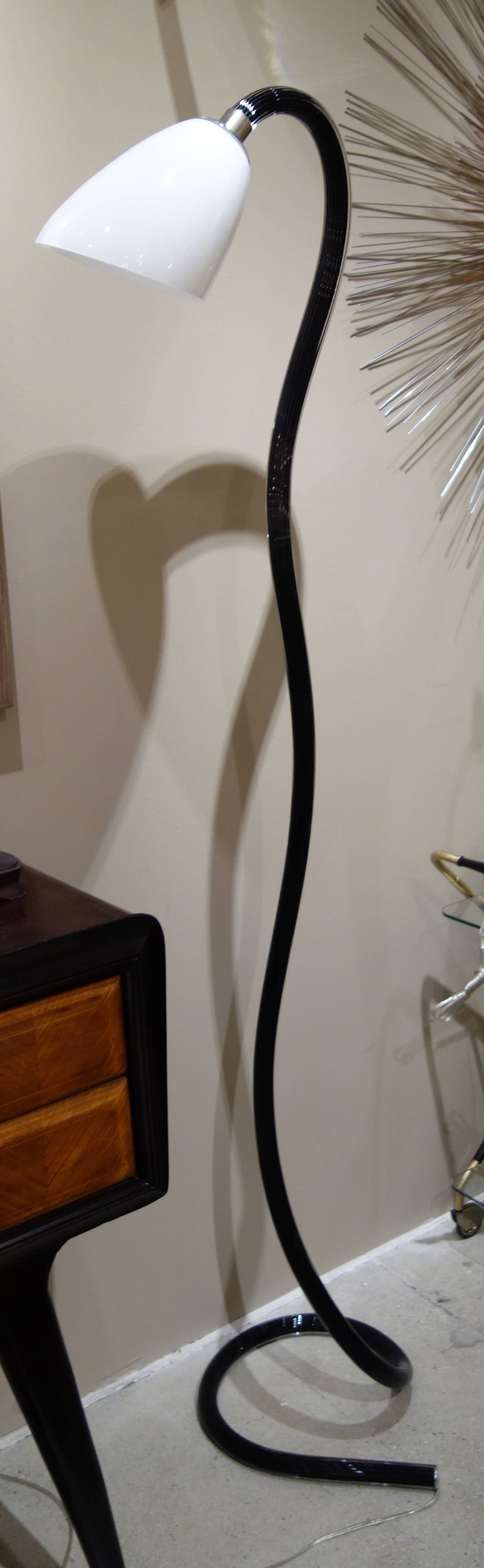 A Mid-Century Italian sculptural floor lamp comprised of a single tubular piece of handblown fluted undulating black cased glass looped at the bottom to form the base, the shaped opaque white glass shade containing a single socket newly wired with a