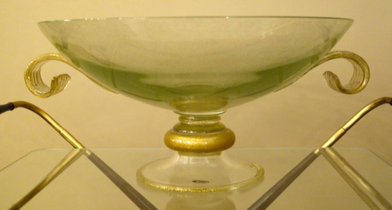 A Mid-Century Italian very large handblown Murano center bowl by Seguso in various shades and saturation of gold and greenish-gold glass of classical pedestal form with downward scrolled fluted handles, with 