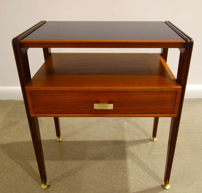 A pair of Italian Mid-Century two tier night Stands with darker wood sides,
black glass tops with one pull drawer with brass pull drawer and brass feet.