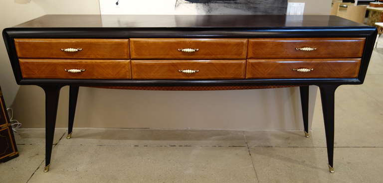 An Italian Mid-Century Modern dresser/sideboard/buffet of rectangular form in contrasting lighter and darker brown woods, the six drawers with matched veneers and decorative strapping with brass pulls, the cross-hatched subtly
shaped apron raised