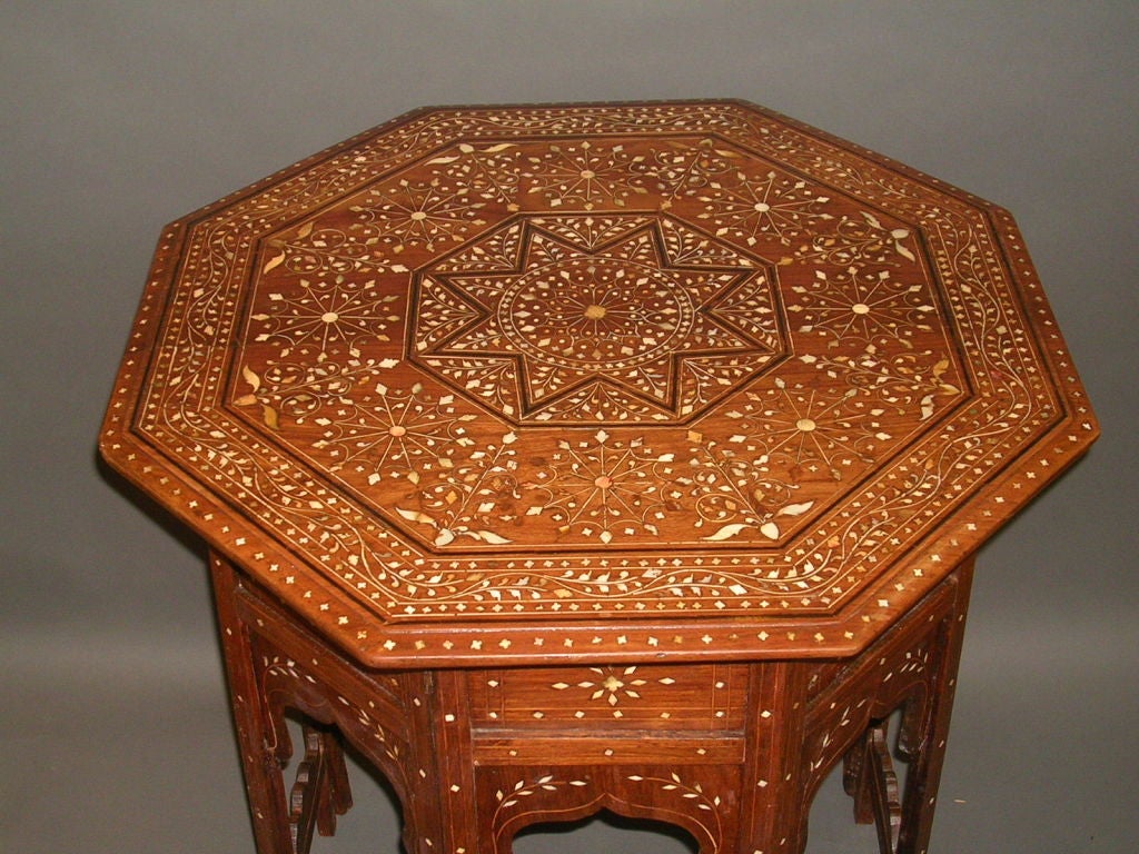 A 19th century Anglo-Indian rosewood table, the octagonal top  of inlaid bone and ebony with a very unusual design featuring the center eight sided star bordered by 12-spoke wheel shaped medallions, with a scrolling outer border of foliate inlay,