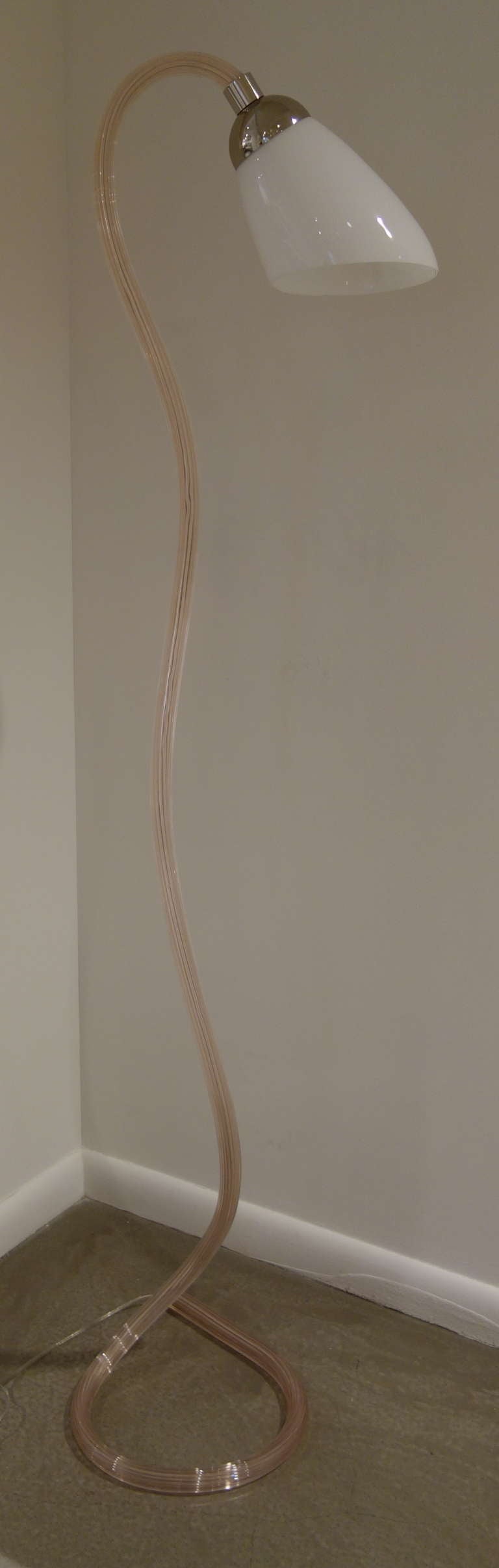 A Mid-Century Italian sculptural floor lamp comprised of a single tubular piece of hand blown fluted undulating blush Murano glass looped at the bottom to form the base, the shaped opaque glass shade containing a single socket newly wired with foot