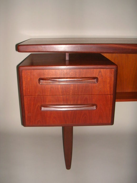 G Plan teak walnut wood trimmed desk/vanity by Danish designer, Ib Kofod-Larsen for E. Gomme Ltd, U.K. in the 1960's featuring the floating top above four drawers with horizontal wood pulls resting on four conical legs.  The back is not