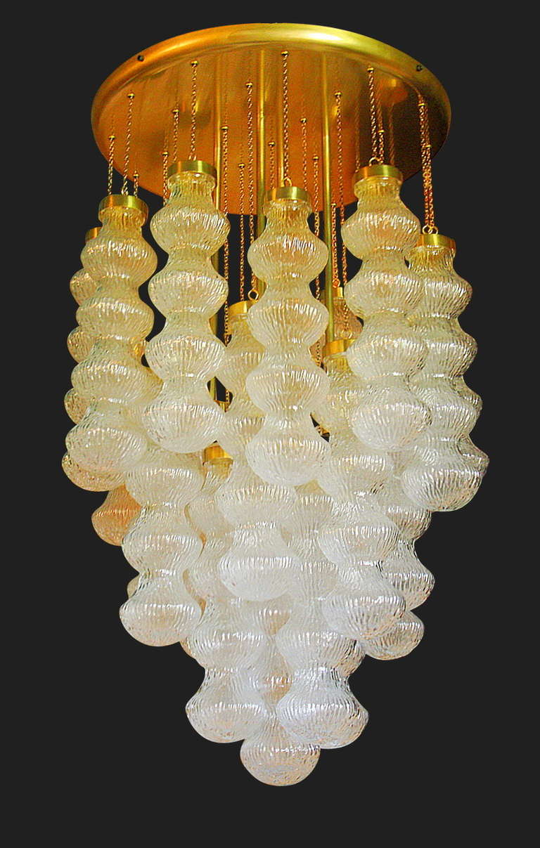 A midcentury Italian four light chandelier by Cenedese comprised of hand blown Murano textured, undulating glass pendants suspended by fine chains of varying lengths from a brass 22.5