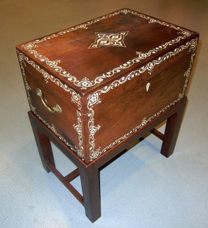 A large antique teakwood campaign style box/side/end table from Vizagapatam featuring a scrolling arabesque
border of inlaid bone on all sides, with a central diamond
design on the lid, original brass handles on the two short sides, the box