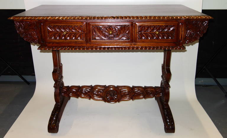 A late 19th century Anglo-Indian rosewood desk or sofa table, the flat top bordered with three pull brass knob drawers bordered by a gadrooned edge on the top and bottom resting on two pierced and carved legs with fluted sleigh feet connected by a