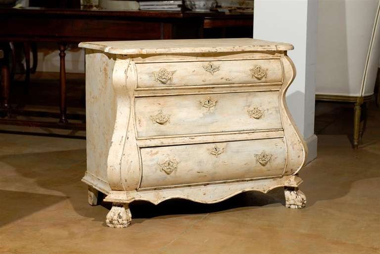 A Baroque style Dutch painted wood bombé three-drawer commode from the late 19th century. This painted commode was born in the Netherlands in the 1890s and features a shaped top with beveled edges over three drawers, the upper one being smaller than