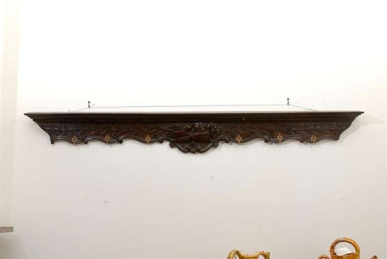 A French wooden rack from the 19th century, with carved foliage and ribbon-tied quiver and arrows. Created in France during the 19th century, this wooden rack features a horizontal shape, adorned with a delicately carved décor showcasing foliage