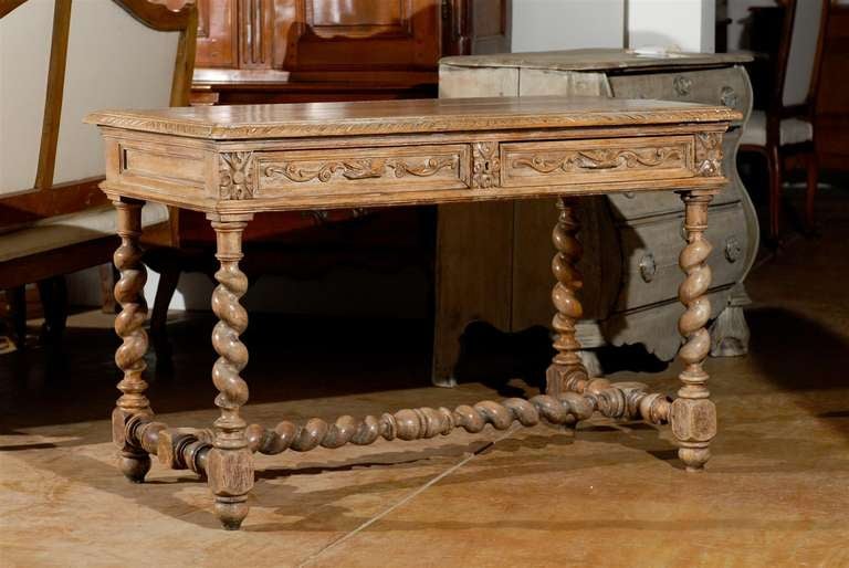 A French Louis XIII style side table with two carved drawers and barley twist legs from the late 19th century. This exquisite French table features a rectangular planked top with outer frame and delicately carved molding, sitting above two frieze