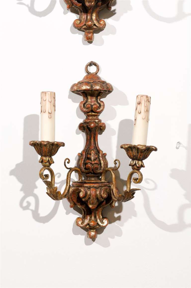 A pair of French Rococo period carved giltwood two-light sconces from the mid 18th century, with scrolling arms and acanthus leaf motifs. Born in France during the reign of King Louis XV, each of this pair of giltwood sconces features a carved