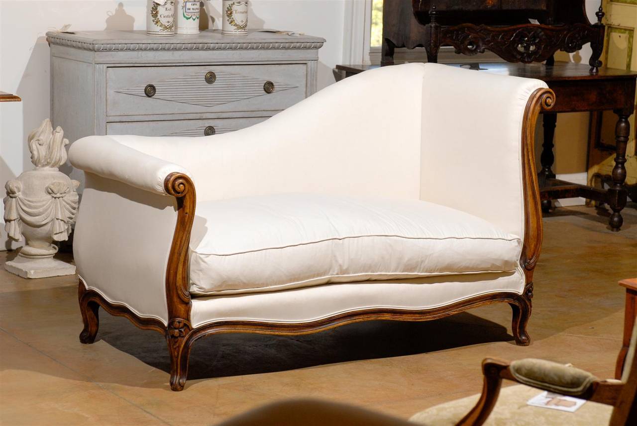 This French Louis XV style walnut upholstered méridienne (French for daybed, also called chaise longue) from the 1830s features a scrolled-out headrest with a lower, also out scrolled, footrest. The gentle curve on the back responds beautifully to