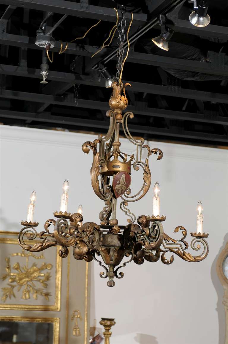 A French Louis XV style painted iron and gilt metal six-light chandelier with crown and coat-of-arms motifs from the late 19th century. This French six-arm chandelier features a painted and gilded armature, composed of an array of volutes and