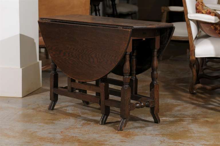 An English 18th century oak oval gateleg drop-leaf table with unusual drake feet. Born in the second half of the 18th century, this English gateleg table features an oval top made of two drop leaves, sitting above a nicely turned base with side