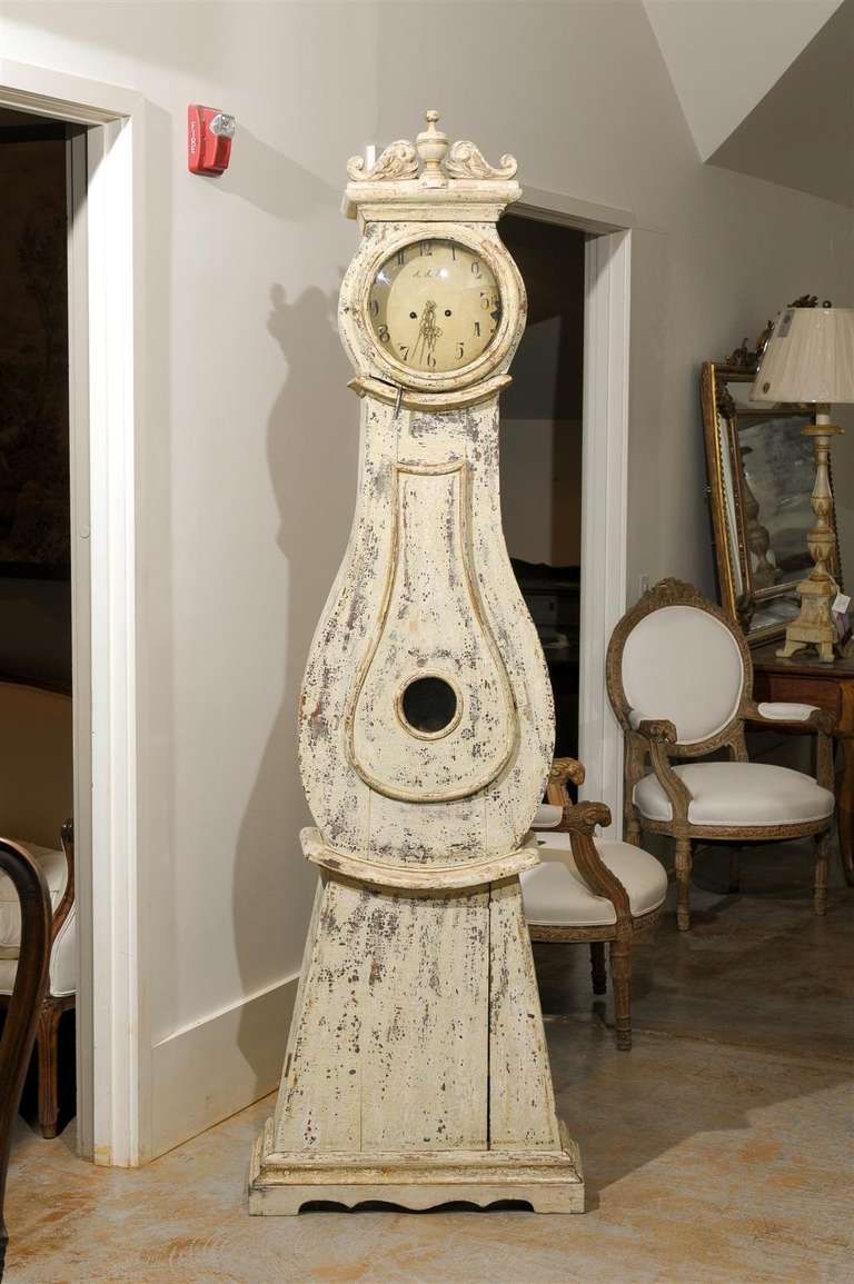 A Swedish wooden longcase clock from the early 19th century with original paint. This exquisite Swedish carved and painted clock, circa 1820 features a central finial in the crest, flanked with delightful volutes adorned with discreet foliage decor.