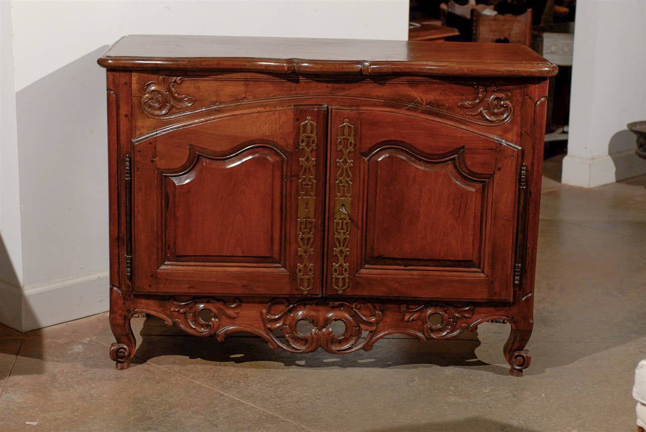 A French period Regence early 18th century walnut buffet with carved skirt and original hardware from Lyon. This French walnut two-door buffet was born in the 1720s in Lyon, the capital of the Rhônes-Alpes region of France, during the Regence era