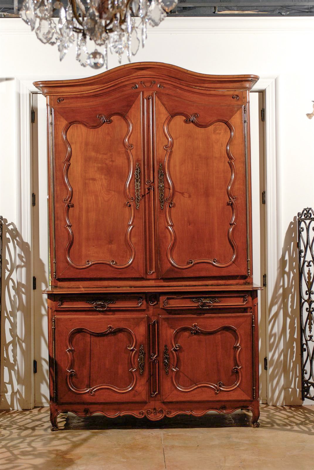 A French Louis XV period cherry buffet à deux-corps from the mid-18th century with original hardware. This French cabinet features a bonnet top surmounting two doors with carved panels and delicate c-scrolls. These small scrolled motifs are repeated