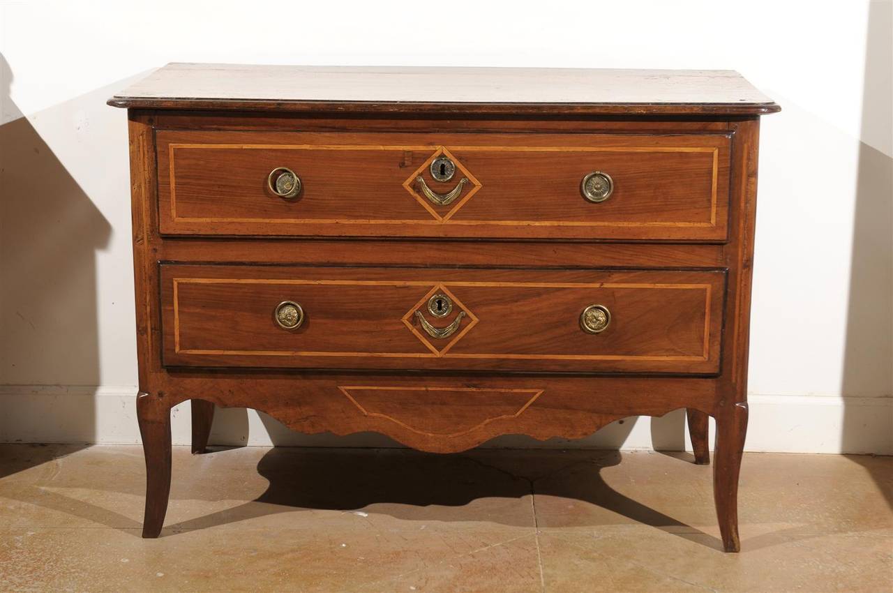 A French Provençale Directoire period two-drawer commode with banded inlay from the late 18th century. This French two-drawer commode was born in the mid-1790s, in the Provence region of Southern France. Featuring a rectangular top with rounded