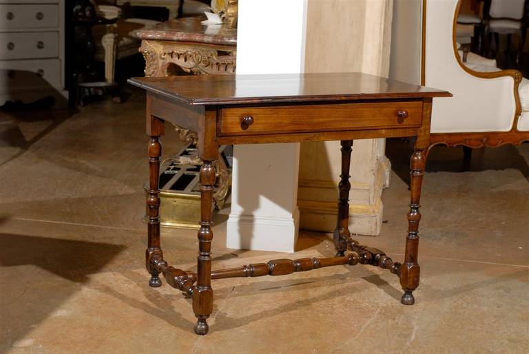 French walnut side table with single drawer, spindle-shaped legs and cross stretcher from the second half of the 19th century. This French side table features a rectangular planked top with bevelled edges sitting above a long single drawer opening