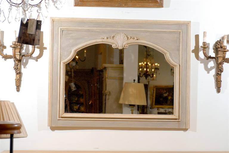 A pair of French Louis XV style painted wood horizontal mirrors from the late 19th century with carved shell motifs. Each of this pair of mirrors features a horizontal Silhouette, painted in a light grey color and accented by cream highlights. Image