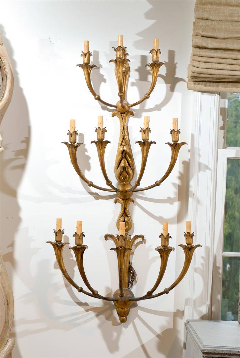 A French gilt metal 12-light tiered sconce from the early 19th century, with foliage motifs. Born in France during the first quarter of the 19th century, this gilt metal sconce features 12 scrolling arms divided into three levels of increasing size.