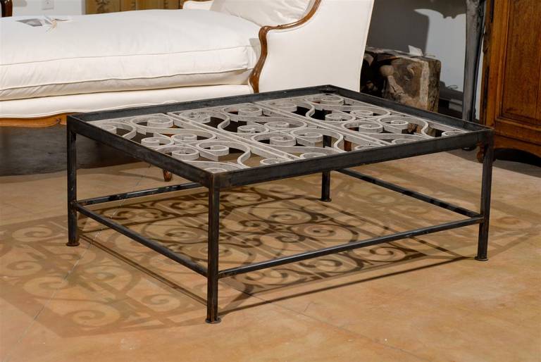 A French mid-19th century balcony ironwork made into a coffee table. This Industrial looking rectangular coffee table is made of a simple black iron frame supporting the delicate painted ironwork of a French balcony, typical of the careful attention