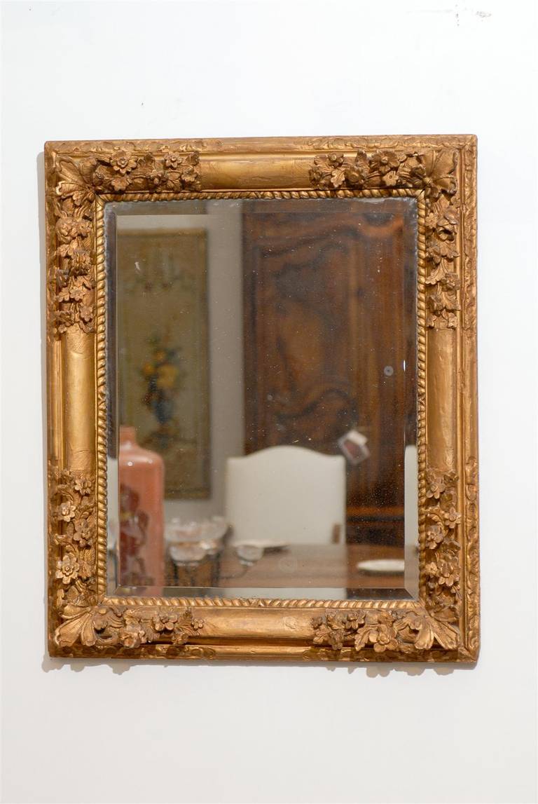 This French late 18th century Régence style carved mirror features an exquisite rectangular giltwood frame adorned along the corners with delicate floral motifs. The quality of the carving is undeniable. The inner frame, closer to the central
