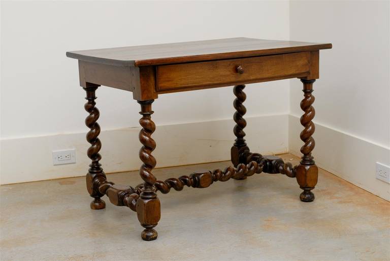 A French Louis XIII style walnut table with single drawer, barley twist legs and cross stretcher from the mid-19th century. This French side table features a rectangular top sitting above a long dovetailed drawer, opening with a round wooden pull.