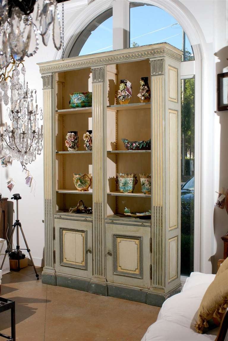 A French Louis XVI style painted wood bookcase attributed to Maison Jansen with open shelves, lower doors and carved pilasters from the late 19th century. This French bibliothèque features a large cornice adorned with a Vitruvian scroll frieze,