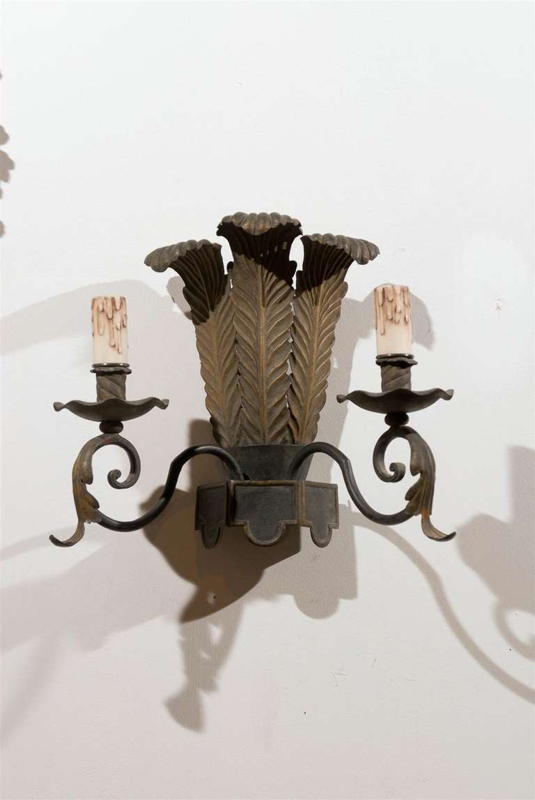 A pair of French Louis XVI style tôle two-light sconces with ostrich plume motifs from the late 19th century. Each of this pair of French sconces features an exquisite grouping of ostrich plumes, flanked with two scrolled arms. Each arm is adorned