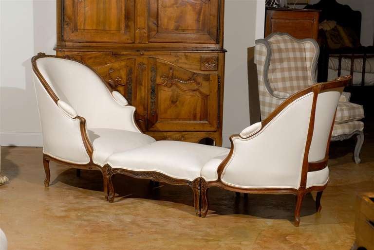 A French Louis XV style walnut Duchesse Brisée with two bergères chairs and their ottoman from the late 19th century and new upholstery. This French chaise longue features three sections, made of two bergères of slightly different dimensions and an
